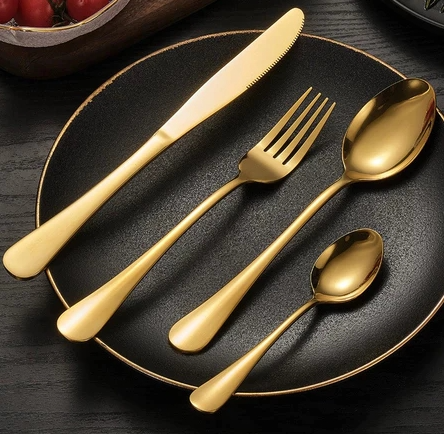 Faqueiro dourado sobre prato preto